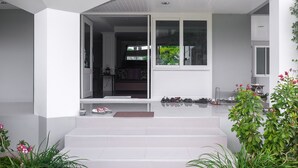 Una casa moderna con un porche cubierto, una escalera que conduce a la entrada y vista al jardín trasero.
