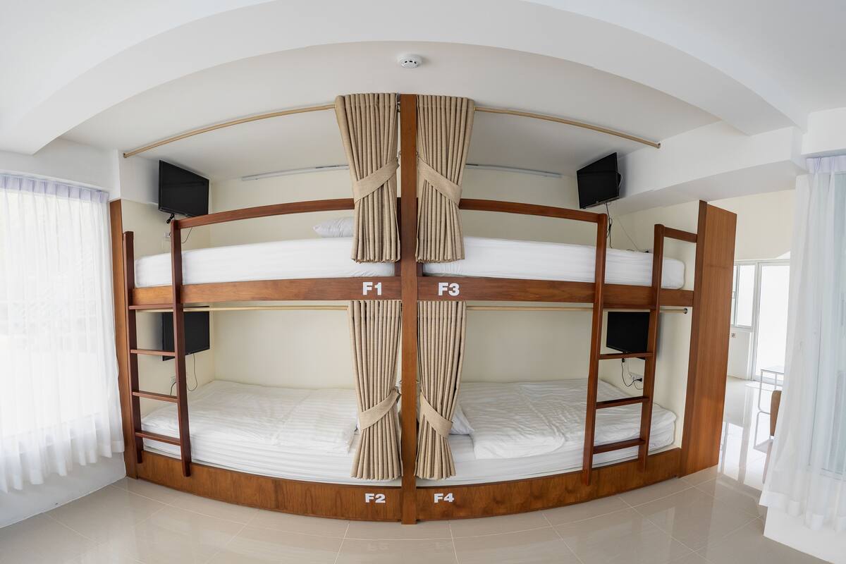 A bunk bed room with a curved ceiling, labeled beds F1 to F4, and a television on each bunk.