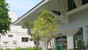 Un patio con un edificio blanco, un árbol y una fuente.