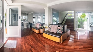 Un espacio habitable amplio con suelo de madera, un conjunto de sofás y una escalera que sube a un nivel superior.