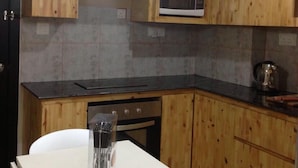 Een keuken met houten kastjes, een magnetron, een fornuis en een wit aanrecht.