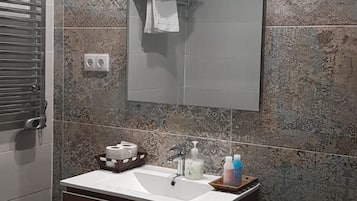 A bathroom with a vanity, a mirror, and a towel rack.