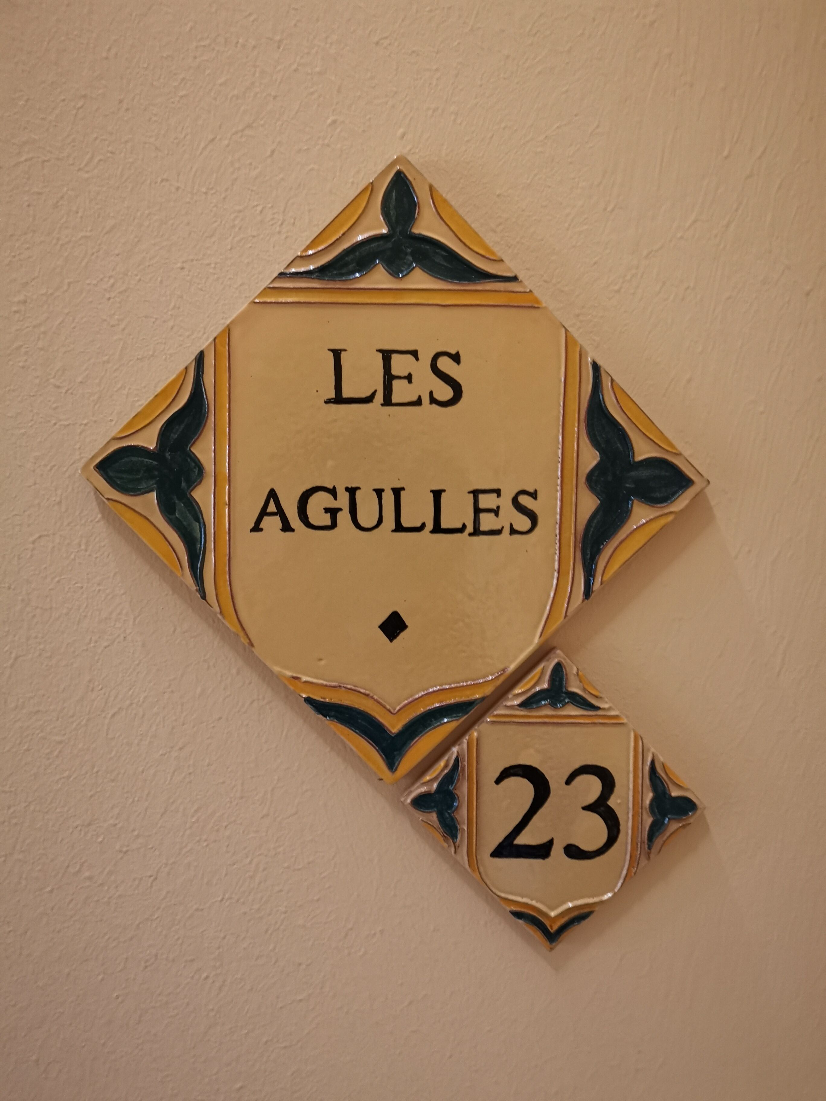 A wall-mounted sign with the text "LES AGULLES" and the number "23".