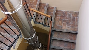 A staircase with a metal railing, a wooden handrail, and a brick wall.