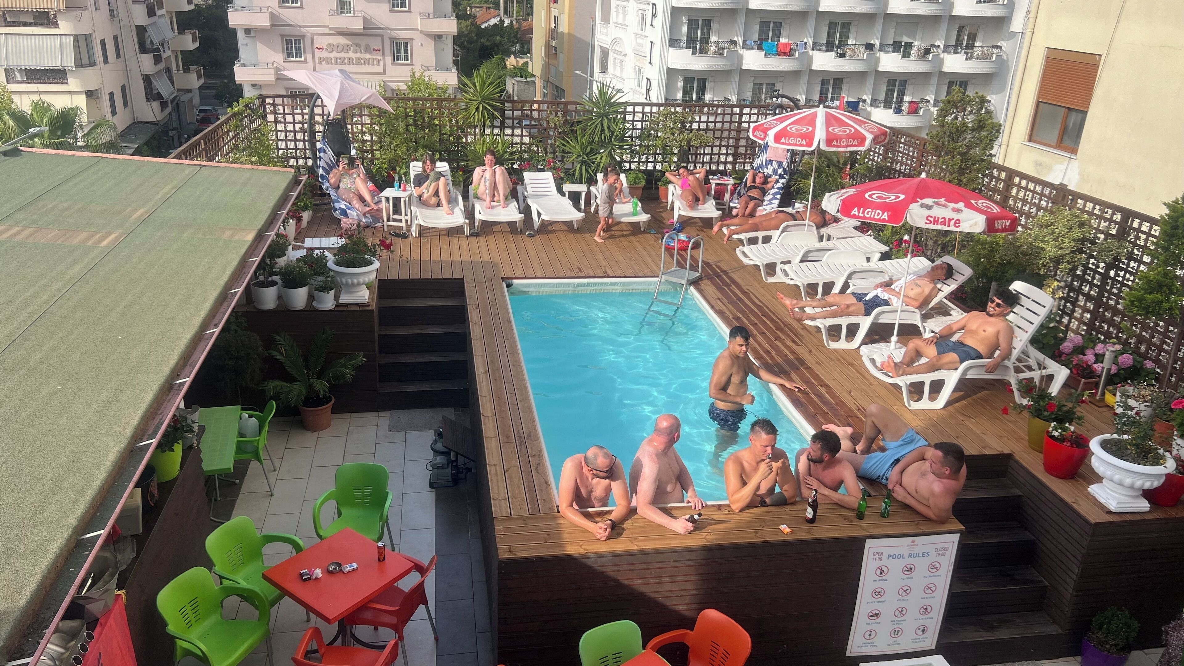 A rooftop pool area with lounge chairs, a pool table, and potted plants.