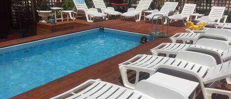A swimming pool with white lounge chairs and a wooden deck.