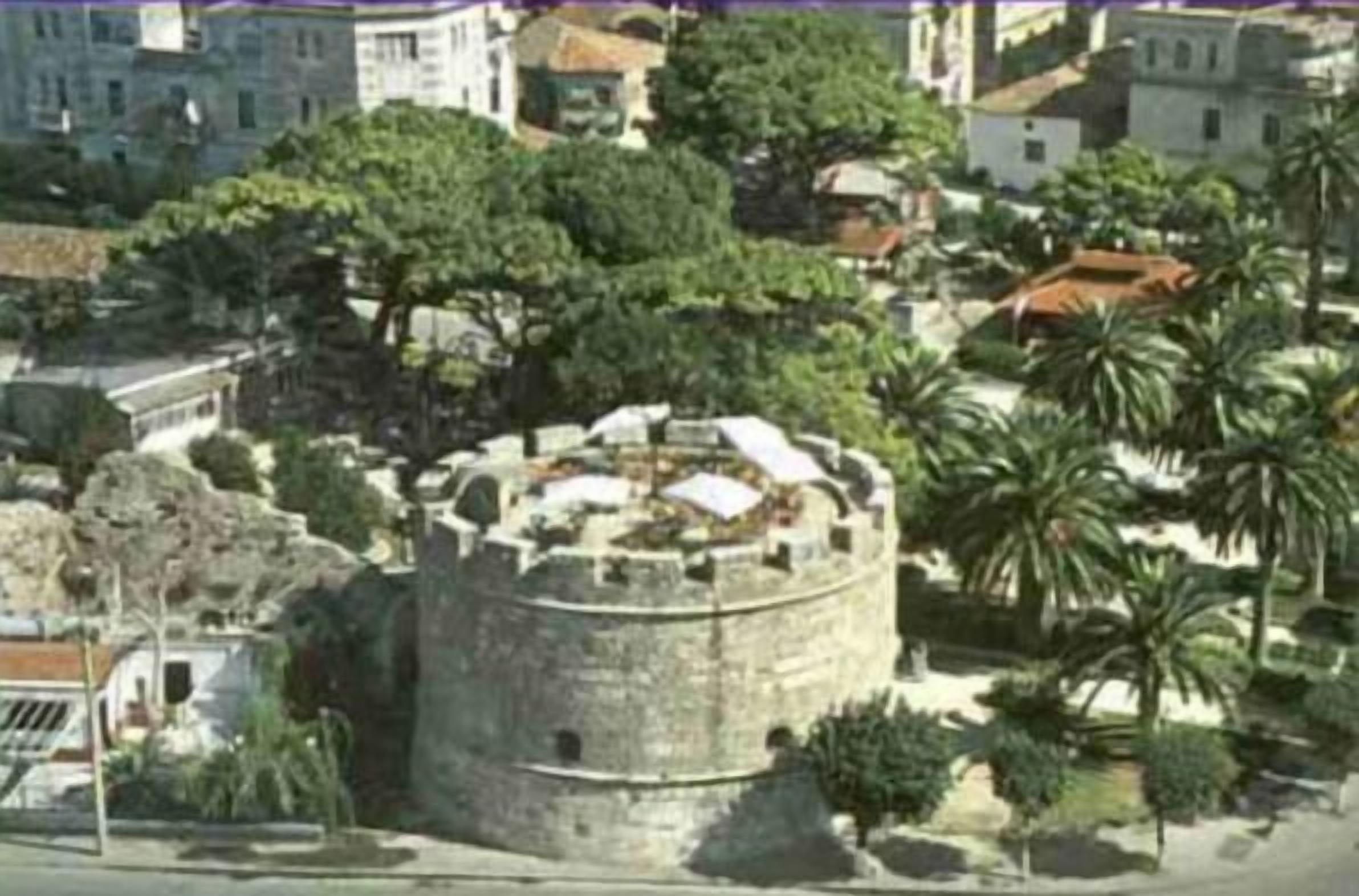 A historic stone fortress with a circular wall and a central courtyard surrounded by trees and buildings.