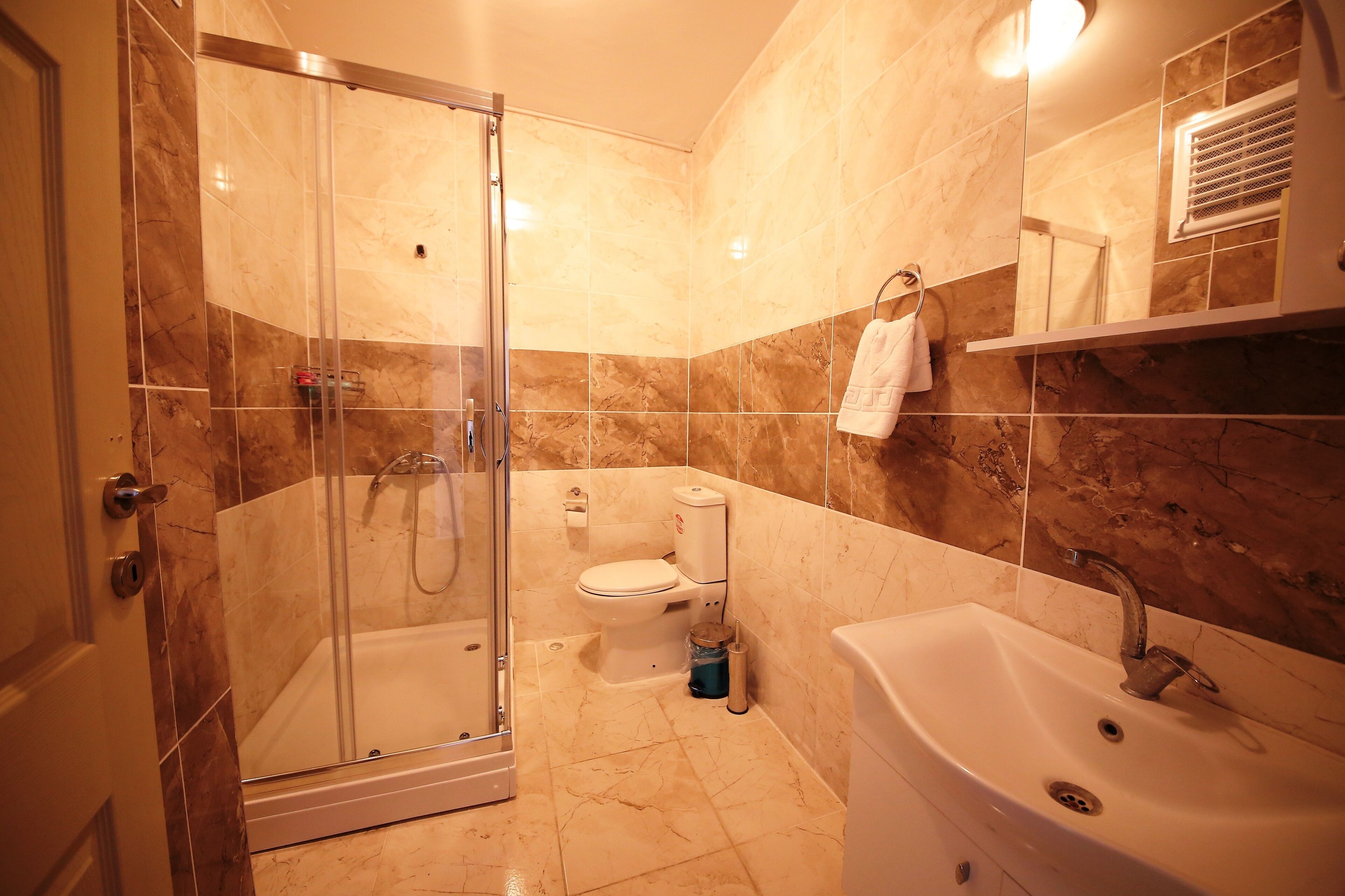 A modern bathroom with a glass-enclosed shower, a standalone bathtub, and a separate sink area.