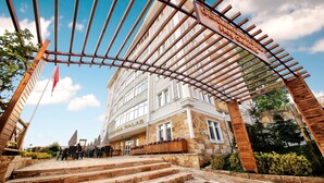 A hotel entrance with a wooden pergola, steps leading up to the entrance, and a clear sky. - Safran Germia Palas (Karabük)