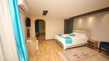 A hotel room with a bed, a desk, a chair, and an air conditioning unit.