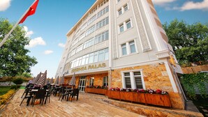 A hotel with a stone facade, multiple windows, and outdoor seating with umbrellas. - Safran Germia Palas (Karabük)