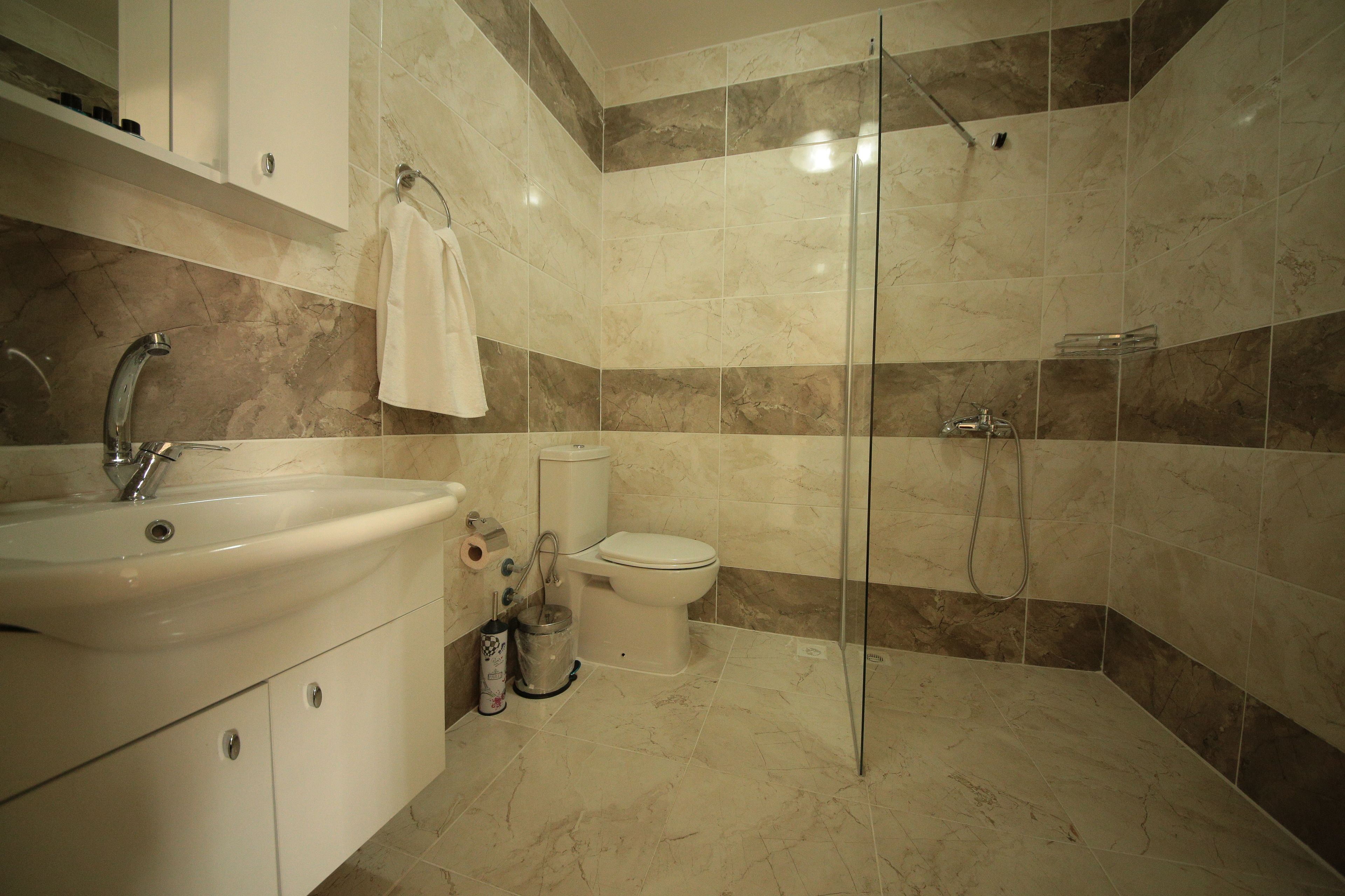 A modern bathroom with a sink, toilet, and glass shower enclosure.