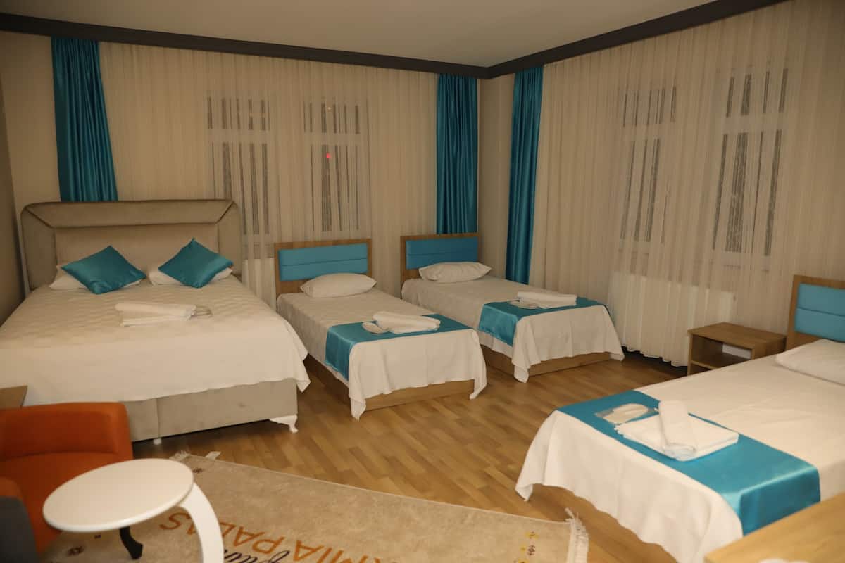 Quarto de hotel com duas camas, uma mesinha e uma cadeira.