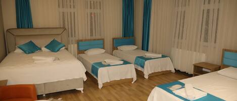 A hotel room with two beds, a small table, and a chair.