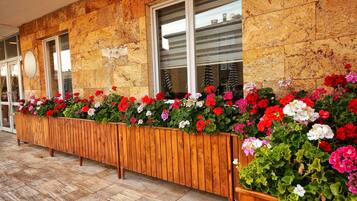 Een houten plantenbak met verschillende bloemen langs een gevel.