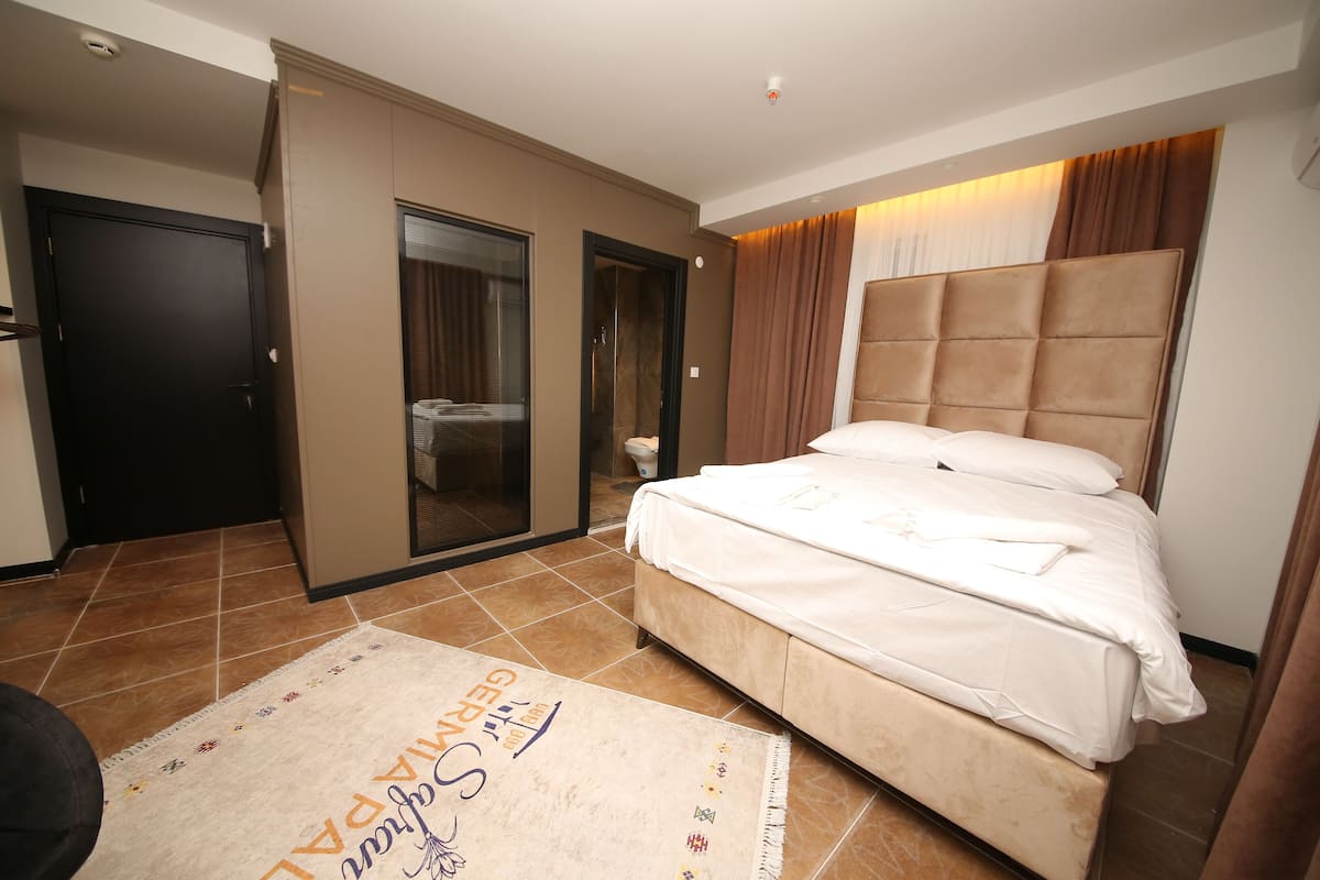 Quarto de hotel com uma cama grande, um espelho, uma porta e piso de azulejos.