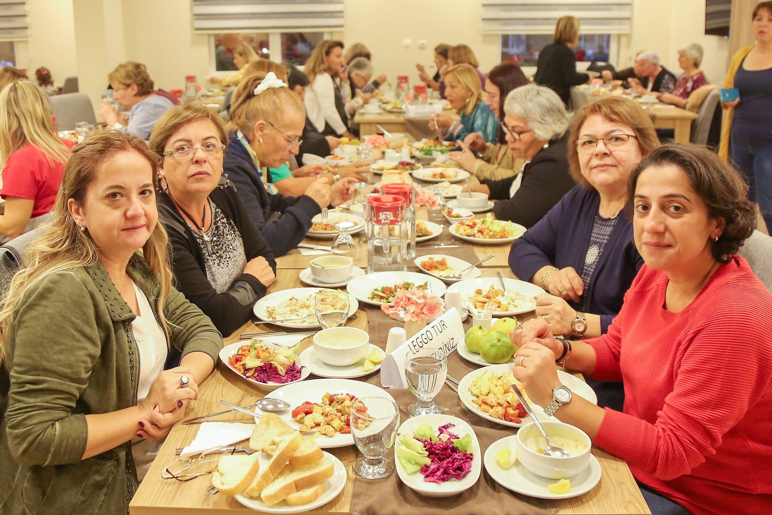 Un grupo de personas cenando en una mesa larga con diversos platos y bebidas.