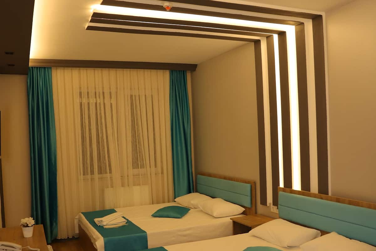 Quarto de hotel com duas camas, uma escrivaninha e um espelho.