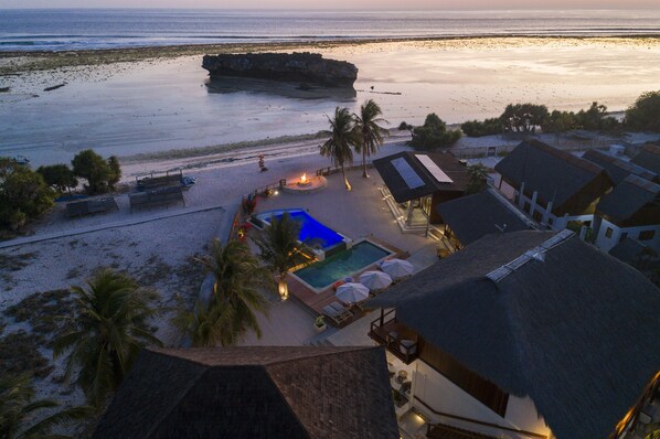 A resort with a swimming pool, beach access, and a view of the ocean.