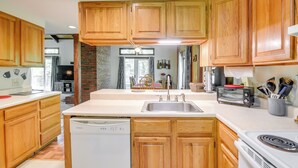 A kitchen with wooden cabinets, a dishwasher, a stove, and a toaster. - New Hampshire Vacation Rental - Walk to Beach! (Madison)