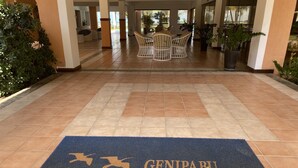 Entrada de un hotel con felpudo que dice "GENIPABU SUMMER HOUSE" y un comedor al fondo.