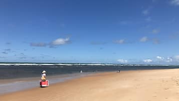 Na praia, areia branca, guarda-sóis, toalhas de praia