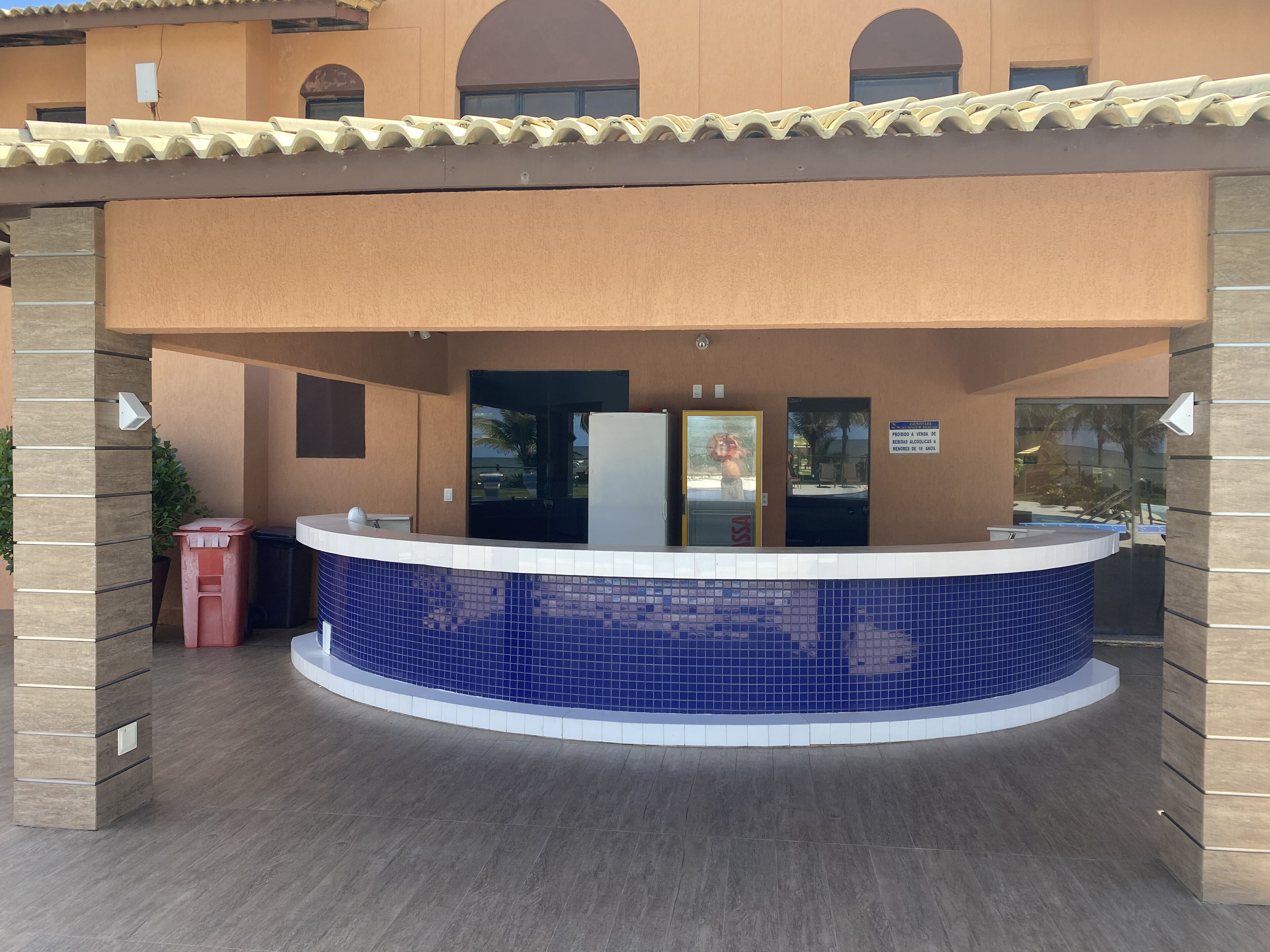 Zona de recepción con mostrador de azulejos azules, un escritorio de recepción y una puerta con un letrero.
