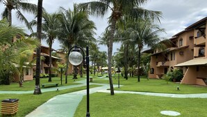 Un resort con palmeras, senderos verdes y edificios con balcones.