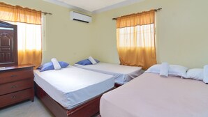 Ett hotellrum med två separata sängar, en byrå i trä och en luftkonditioneringsanläggning.