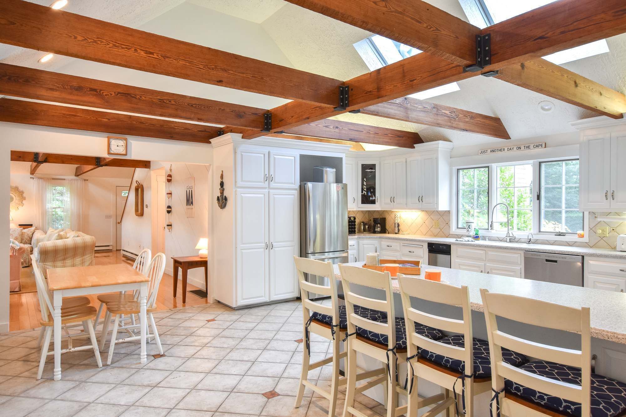A spacious kitchen with white cabinets, a stainless steel refrigerator, and a large island with bar stools.