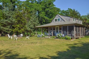 A two-story house with a covered porch, surrounded by a well-maintained lawn and trees.