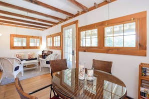 A room with a glass table, wicker chairs, a sofa, and wooden beams on the ceiling. - Private beach access Wrap around porch! (Orleans)