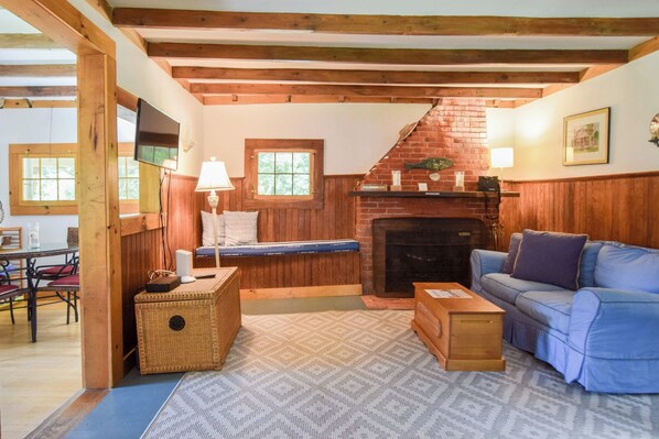 A cozy living room with a fireplace, a television, and a sofa. - Private beach access Wrap around porch! (Orleans)