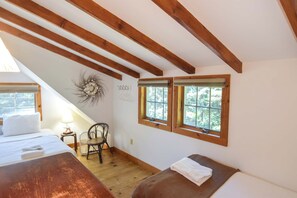 A bedroom with a sloped ceiling, wooden beams, a bed, a chair, and two windows with blinds. - Private beach access Wrap around porch! (Orleans)