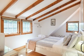 Une chambre à coucher avec un lit, une table de chevet, une fenêtre et un tableau au mur.