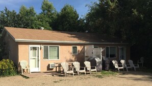 Il s’agit d’un bâtiment d’un seul étage, avec un toit brun et des murs de couleur beige. Plusieurs chaises Adirondack sont disposées devant le bâtiment, et un barbecue couvert est visible sur le côté droit.