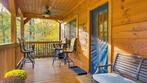 A wooden deck with a table and chairs, a bench, and a door with a blue frame. - 25-Acre Mountain Retreat w/ Trails, Pond, Hot Tub (Penrose)