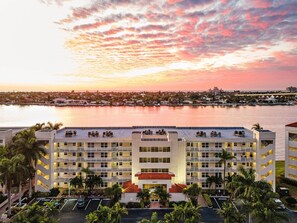 A multi-story hotel with a central atrium, parking lot, and a waterfront view.