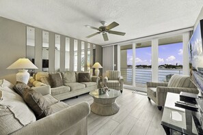 A modern living room with a sofa, armchairs, a coffee table, and a television.