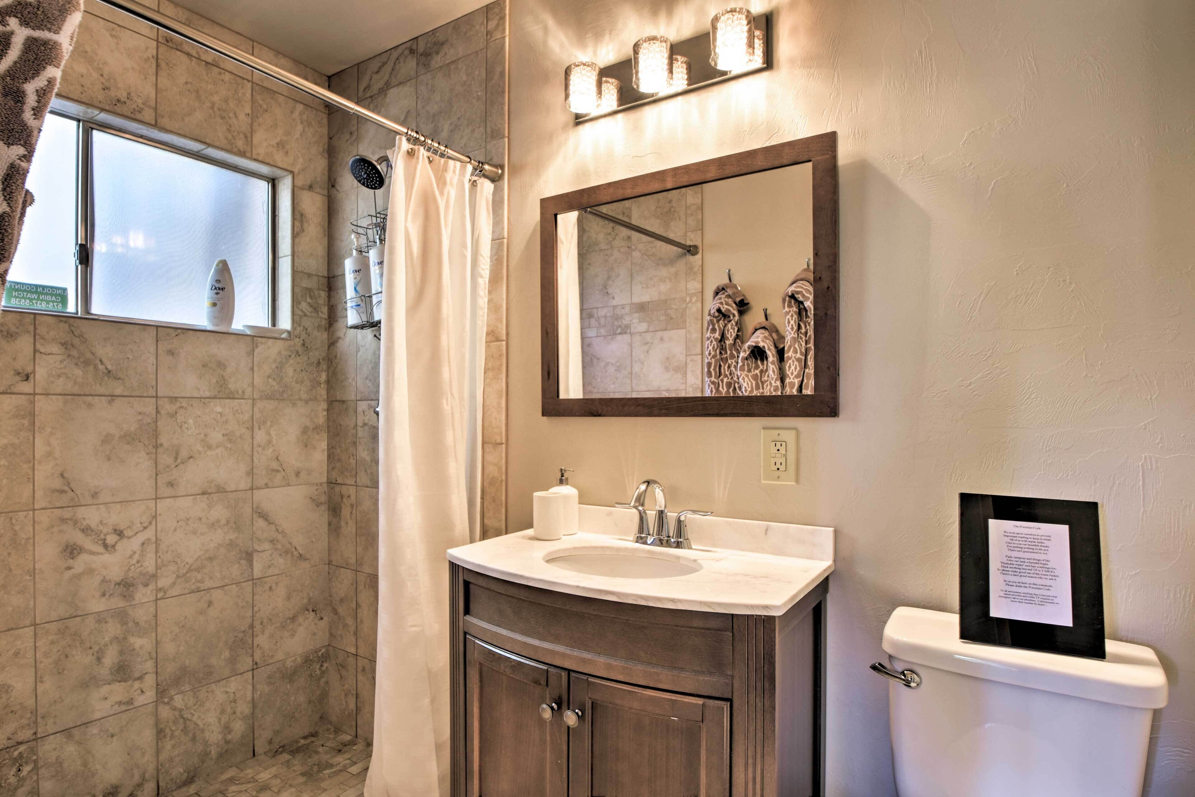 A bathroom with a marble floor, a shower with a glass door, a vanity with a sink and mirror, and a toilet.
