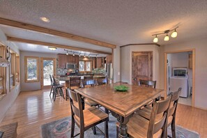 Une cuisine spacieuse avec des meubles en bois, une grande table à manger et un réfrigérateur.