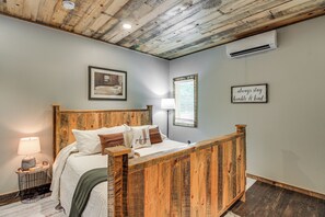 A bedroom with a wooden bed frame, a bedside lamp, a framed picture on the wall, and a motivational quote sign. - Modern Lakeside Chalet on Crow Wing Chain w/ Dock! (Nevis)