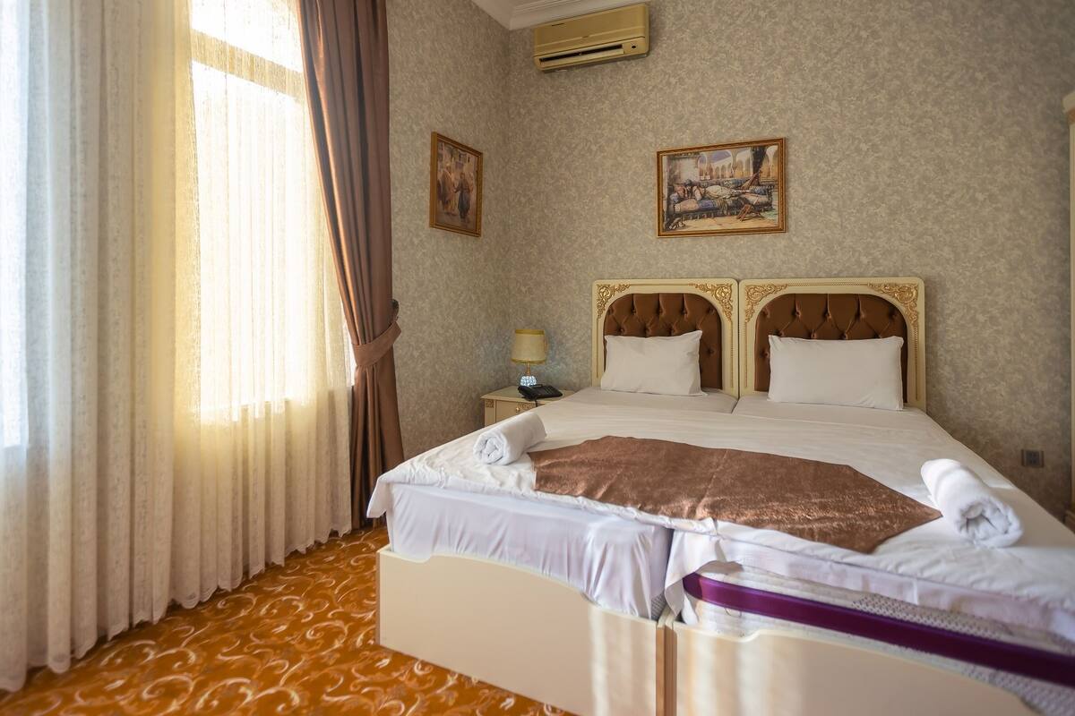 Ein Hotelzimmer mit einem großen Bett, einem Nachttisch mit Lampe und zwei gerahmten Bildern an der Wand.
