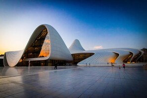 A modern architectural building with a unique curved design and large glass windows. - Iva Old City Hotel (Baku)