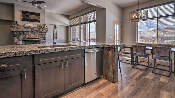 A kitchen with dark wood cabinets, a stone fireplace, and a dining area with four chairs.