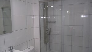 Un bagno con piastrelle bianche, un lavandino, uno specchio e un box doccia.