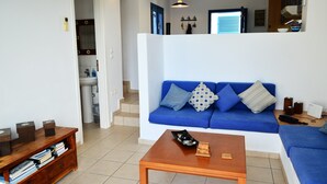 Un salon avec un canapé bleu, une table basse en bois et une bibliothèque.