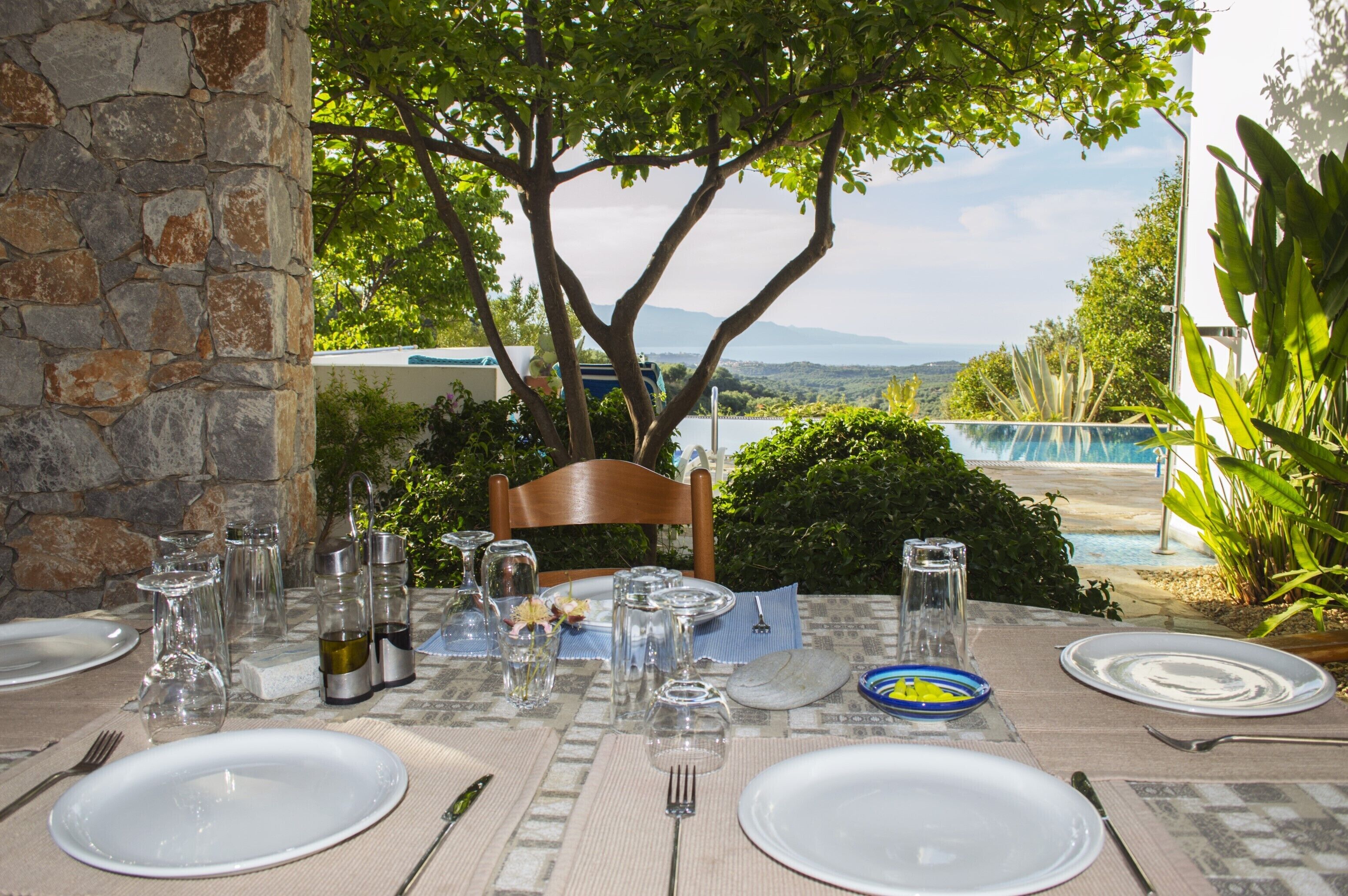 A table set for dining with a view of a pool and mountains.