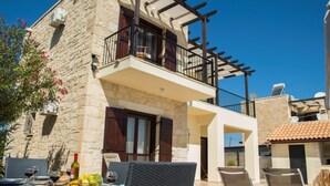 Un edificio de piedra con balcón, mobiliario exterior y piscina.
