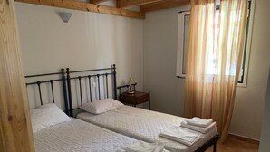 Ein Doppelbett mit Holz-Kopfteil, ein Nachttisch mit Lampe und ein Fenster mit Vorhängen.